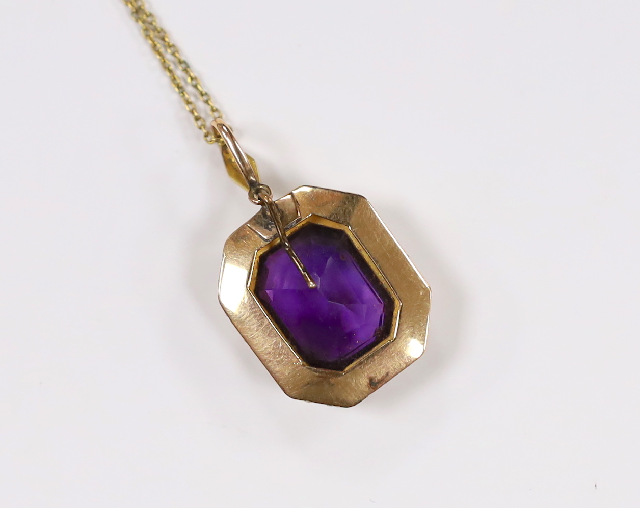 An Edwardian 15ct, amethyst and seed pearl cluster set pendant, overall 33mm, on a 9ct chain, 70cm, chain, 2.5 grams.